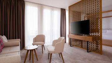 A hotel room with a sofa, two chairs, a coffee table, a TV on a wooden stand, and a decorative screen.