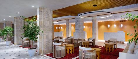 A spacious lobby with a reception desk, seating area, and potted plants.