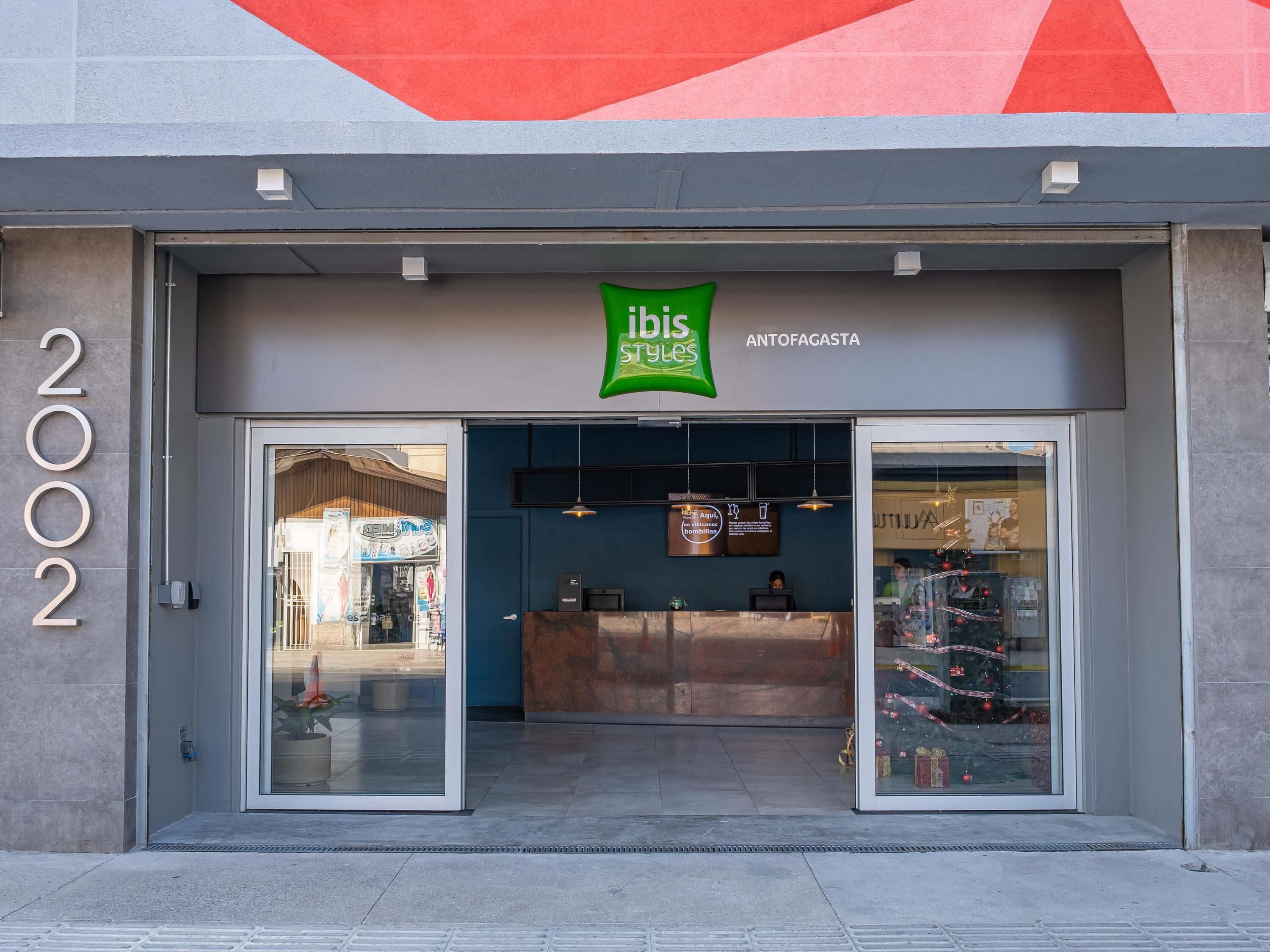 A building entrance with a green sign above the door, a reception desk inside, and a glass display case with items.