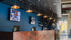 A reception desk with a blue wall, overhead lighting, and a framed photo collage. - Ibis Styles Antofagasta (Antofagasta)