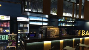 A bar area with seating, shelves of bottles, and a sign indicating the bar opens at 12 AM. - Ibis Styles Antofagasta (Antofagasta)
