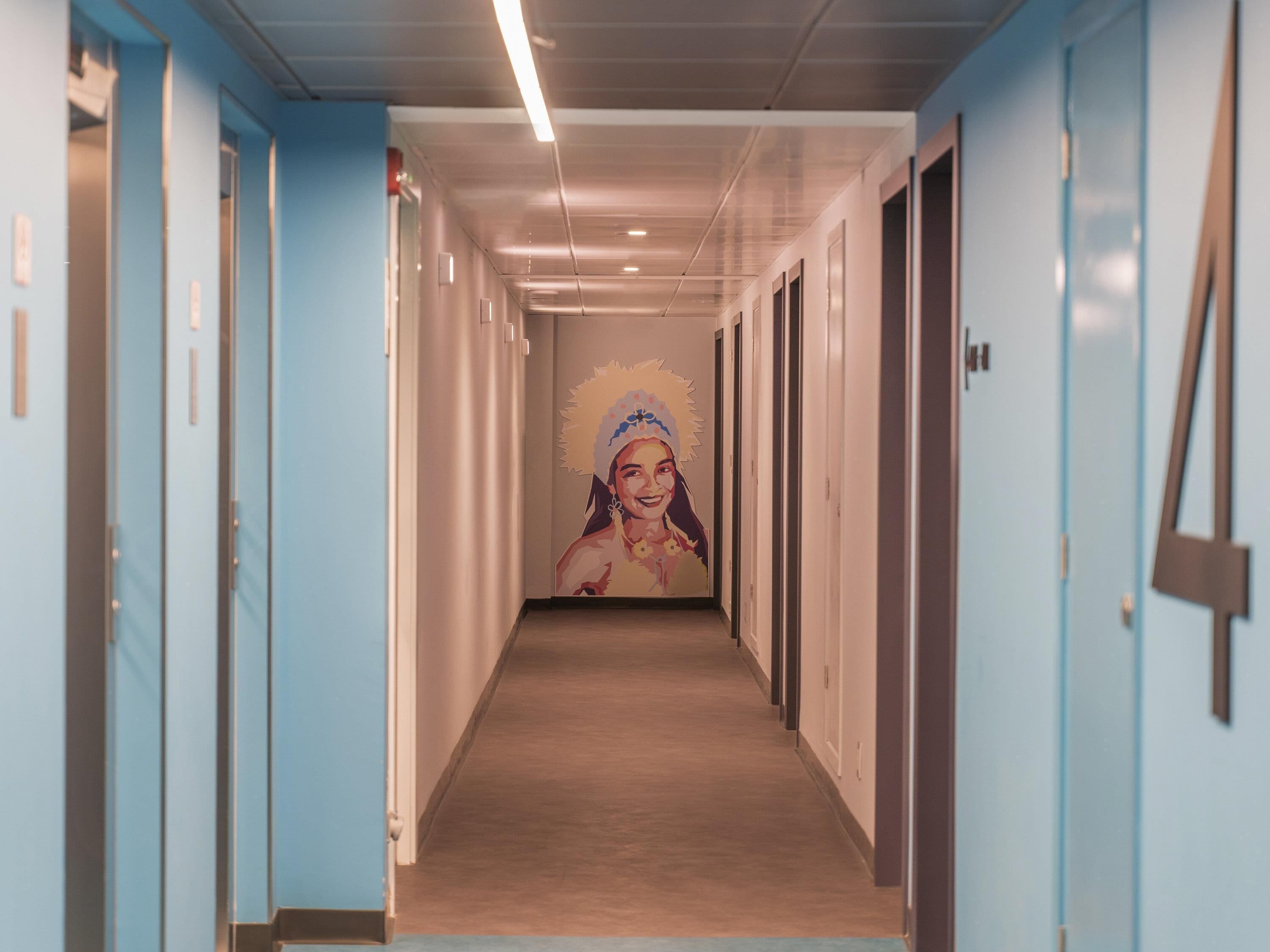 A long, narrow hallway with light blue walls and doors on both sides.