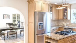 A kitchen with wooden cabinets, stainless steel appliances, granite countertops, and pendant lighting.