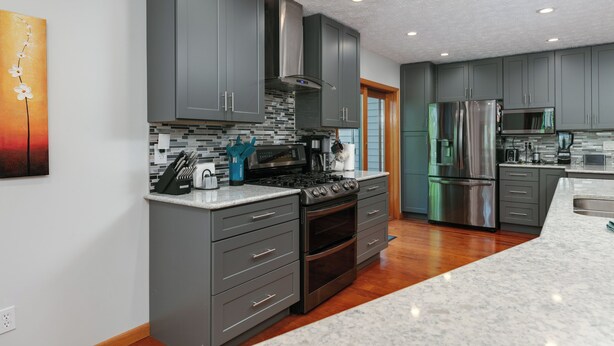 Una cocina moderna con armarios grises, una estufa de acero inoxidable y una isla grande con microondas.