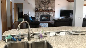 Una cocina moderna con chimenea de piedra, un comedor con televisor y una sala de estar con sofá.