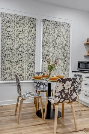 Un comedor con dos sillas, una mesa y un florero con flores.