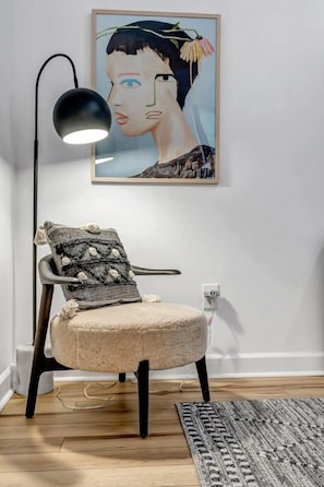 A chair with a fluffy cushion and a patterned pillow, a black floor lamp, and a framed artwork on the wall. - Forth House – Stylish & Cozy 1 BR Apt in Springfield (Jacksonville)