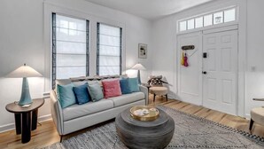 A modern living room with a sofa, two lamps, a coffee table, and a door with a coat rack. - Forth House – Stylish & Cozy 1 BR Apt in Springfield (Jacksonville)