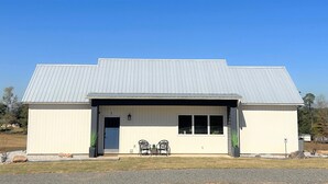 A single-story building with a metal roof, a front door, and two windows.