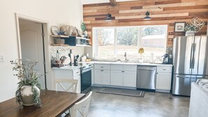 A modern kitchen with white cabinets, a stainless steel refrigerator, and a wooden ceiling.