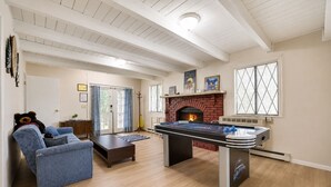Una sala de estar con mesa de fútbol, chimenea y sofá azul.