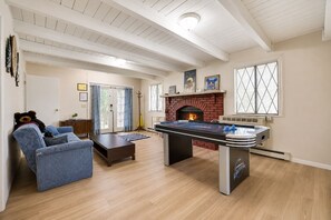 A living room with a foosball table, a fireplace, and a blue sofa. - Walk to Beach, Spacious Backyard (Lake Ariel)