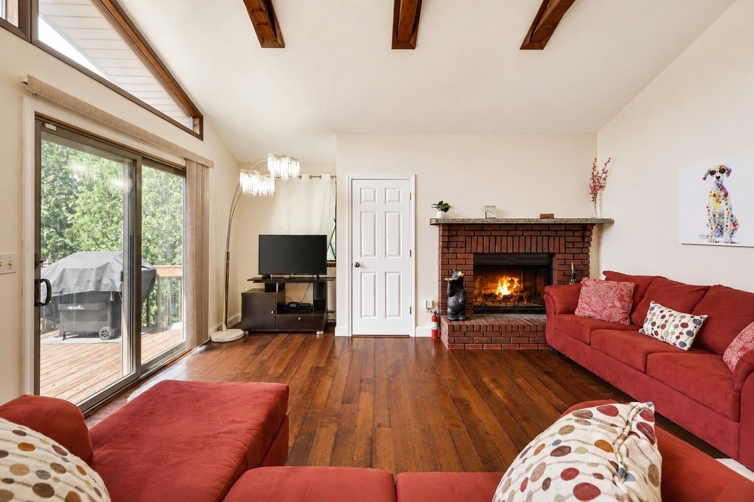 A living room with a fireplace, a television, and a red sofa.