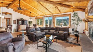 Un salón espacioso con un amplio sofá modular, una chimenea y un techo alto de madera.