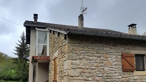 A stone house with a small porch, a chimney, and a satellite dish.