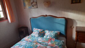 A bedroom with a bed, a nightstand, a wall clock, and a window with curtains.