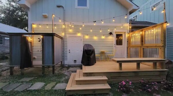 Relax on the deck with a wooden bench and table, surrounded by a stone pathway and a covered seating area.
