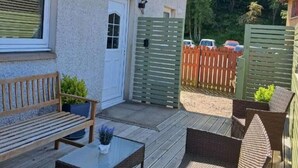 Een overdekt terras buiten met rieten meubels, een bank en een tafel.