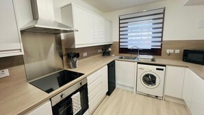 Eine moderne Küche mit Einbauherd, Backofen, Geschirrspüler und Waschmaschine.