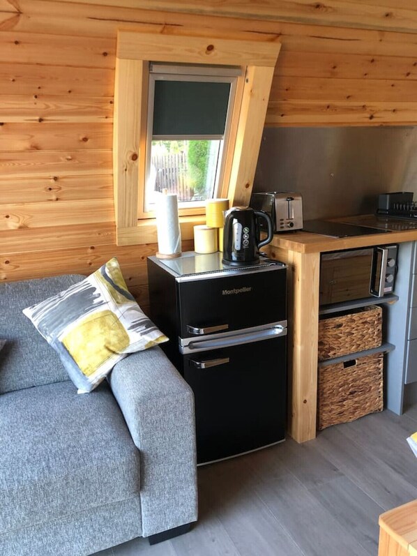 A compact kitchenette with a black refrigerator, a coffee maker, and a toaster.