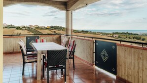 Un balcon avec une table et des chaises, offrant une vue sur un paysage côtier.