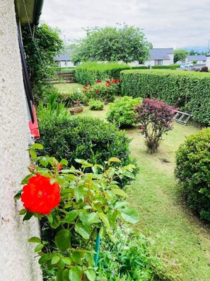 Enjoy a serene outdoor space with a garden featuring hedges, plants, and a water feature.