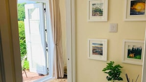A room with a view through a glass door to a patio, a small table with a plant and a book, and several framed pictures on the wall. - The Nell in Central Fort William (Fort William)