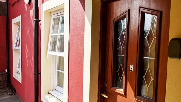 Un bâtiment rouge avec une fenêtre blanche et une porte en bois portant le numéro « 2 ».