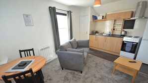 Een kleine woonruimte met een bank, een eettafel en een kitchenette.