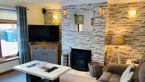 A living room with a stone fireplace, a flat-screen TV, a sofa, and a coffee table. - Aonachan Cottage in the village of Spean Bridge (Spean Bridge)