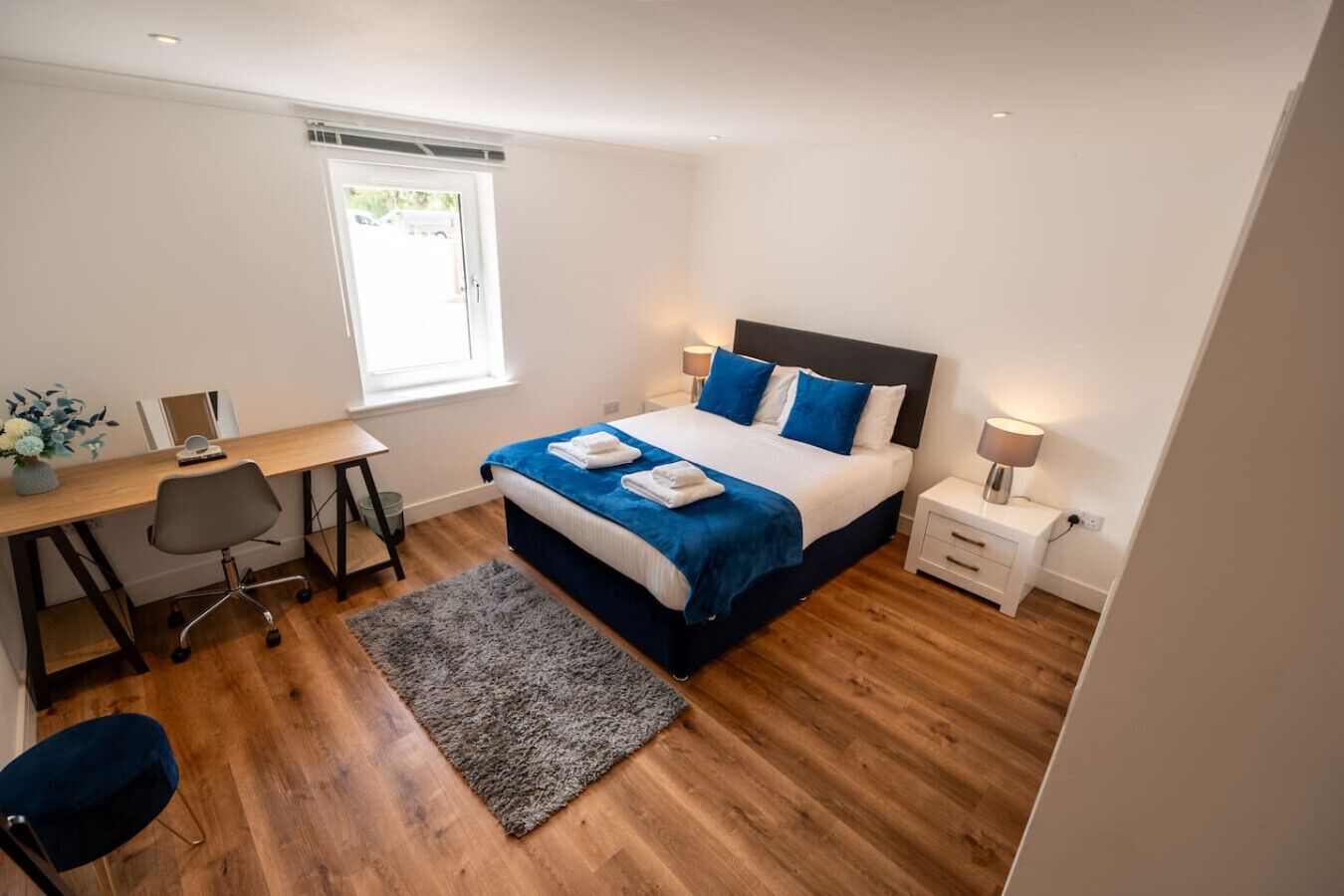 Ein modernes Schlafzimmer mit einem großen Bett, einem Schreibtisch und einem Stuhl.