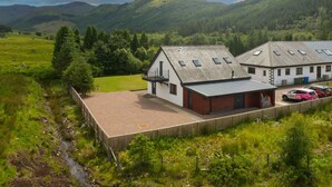 A rural property with a large open area, a farmhouse, and a carport. - Achintee Cottages No 1 (Highland Council)