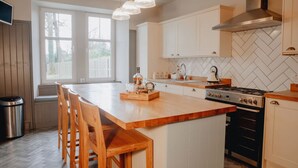 Een keuken met een groot eiland, houten stoelen, een fornuis en een backsplash met een visgraatpatroon.