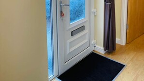 A white door with a frosted glass panel, a brown curtain, and a black mat at the entrance.
