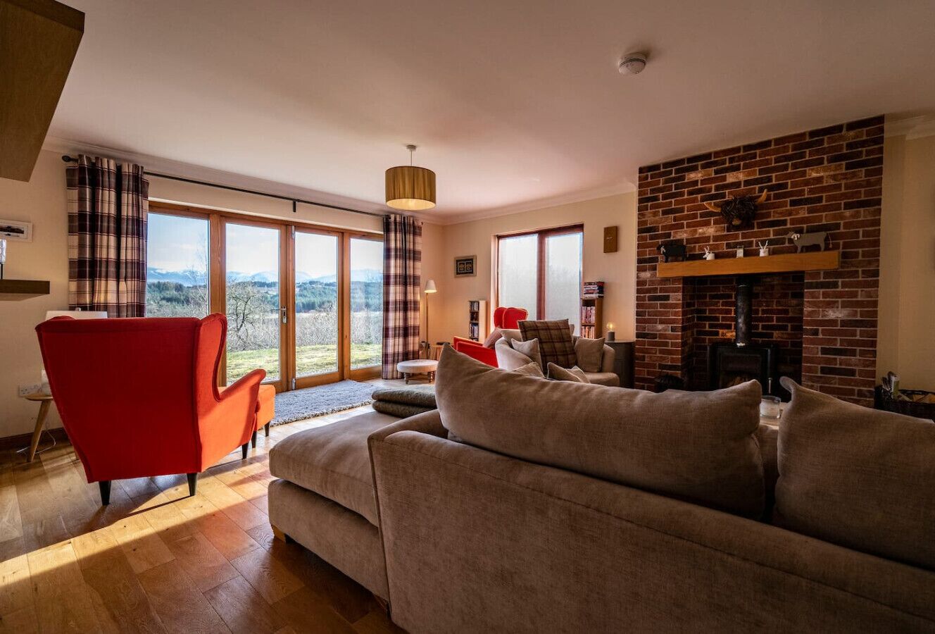 Una sala de estar con un ventanal grande, una chimenea y un sillón rojo.