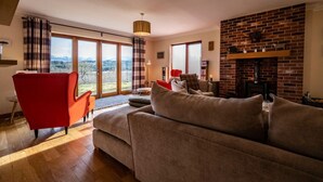 Una sala de estar con un ventanal grande, una chimenea y un sillón rojo.