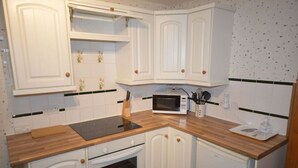 Una cocina con armarios blancos, un microondas, una encimera de madera y un fregadero.