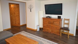 Una sala de estar con un televisor de pantalla plana, muebles de madera y una alfombra estampada.