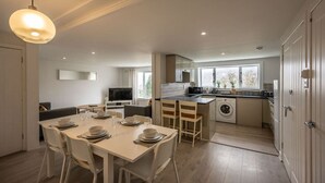 A modern kitchen with a dining area, a washing machine, and a TV. - Highland Lookout in Fort William (Highland Council)