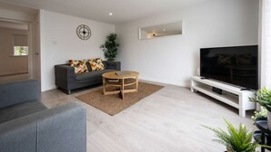 A modern living room with a grey sofa, a coffee table, a TV on a stand, and a large mirror on the wall. - Highland Lookout in Fort William (Highland Council)