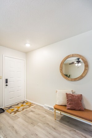 Enter a stylish space with a white door, patterned rug, and comfortable bench.