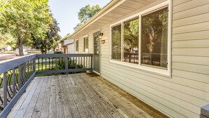 A wooden deck with a railing, large windows, and a door.