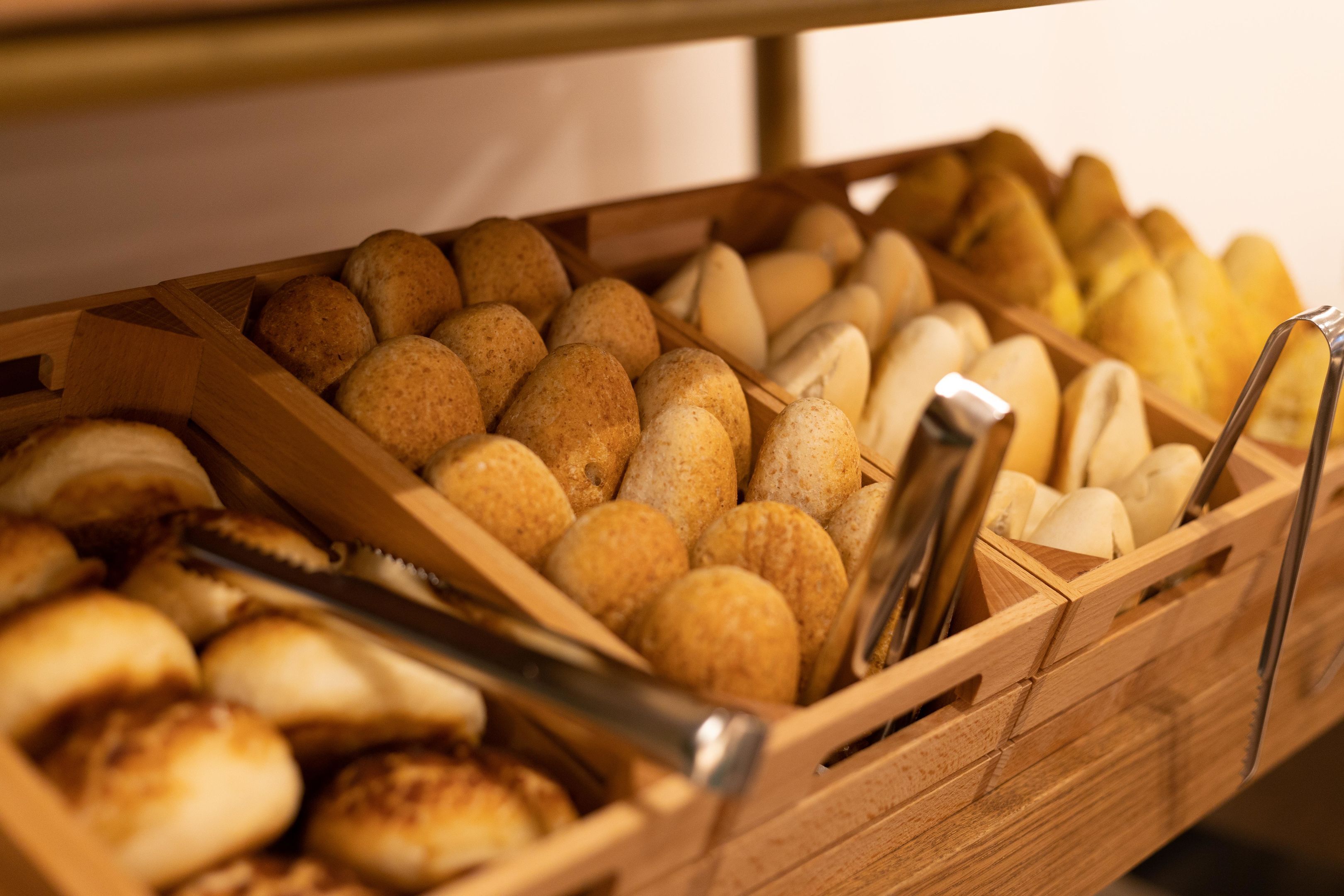 A wooden bread basket filled with various types of bread.