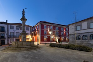 A square with a central fountain and surrounding buildings, including a red building with a sign reading "ESCOLA MASTRO JORRO". - AP Dona Aninhas  (Viana do Castelo)