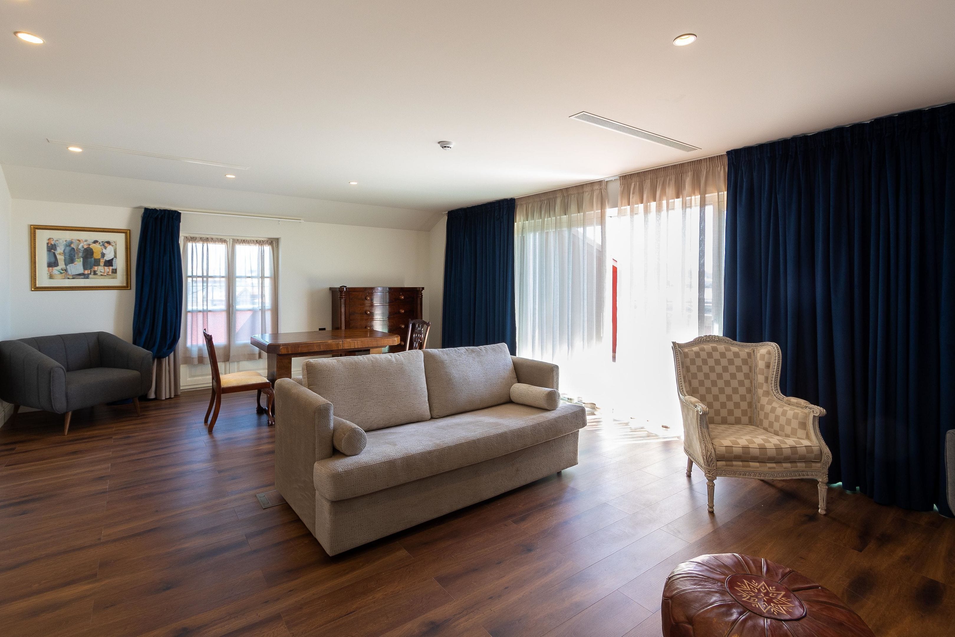 A living room with a sofa, armchair, ottoman, and a dining table with chairs.