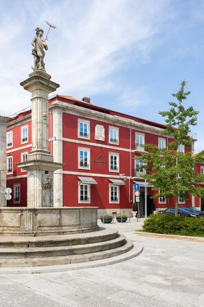 A red building with a statue on a pedestal in front. - AP Dona Aninhas  (Viana do Castelo)