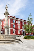 Un edificio rojo con una estatua sobre un pedestal.