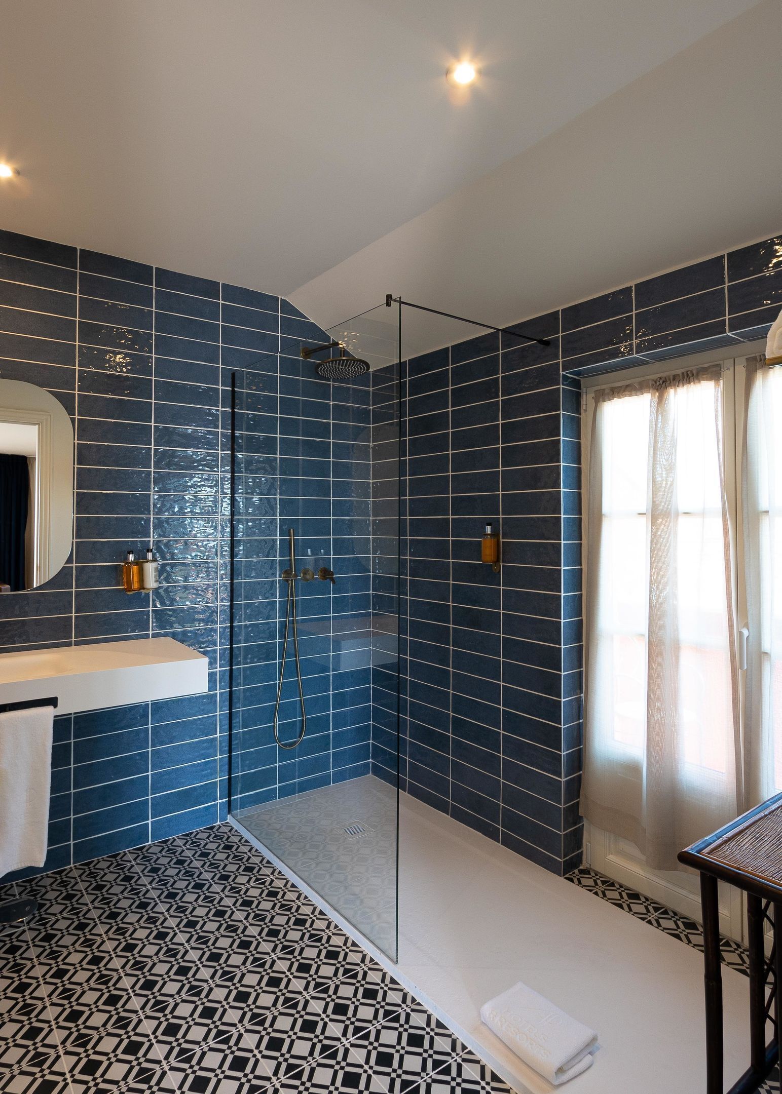 Une salle de bain moderne avec une douche à parois de verre, un lavabo blanc et un carrelage décoratif.
