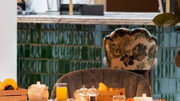 A breakfast table with various dishes, a teapot, and a glass of orange juice.