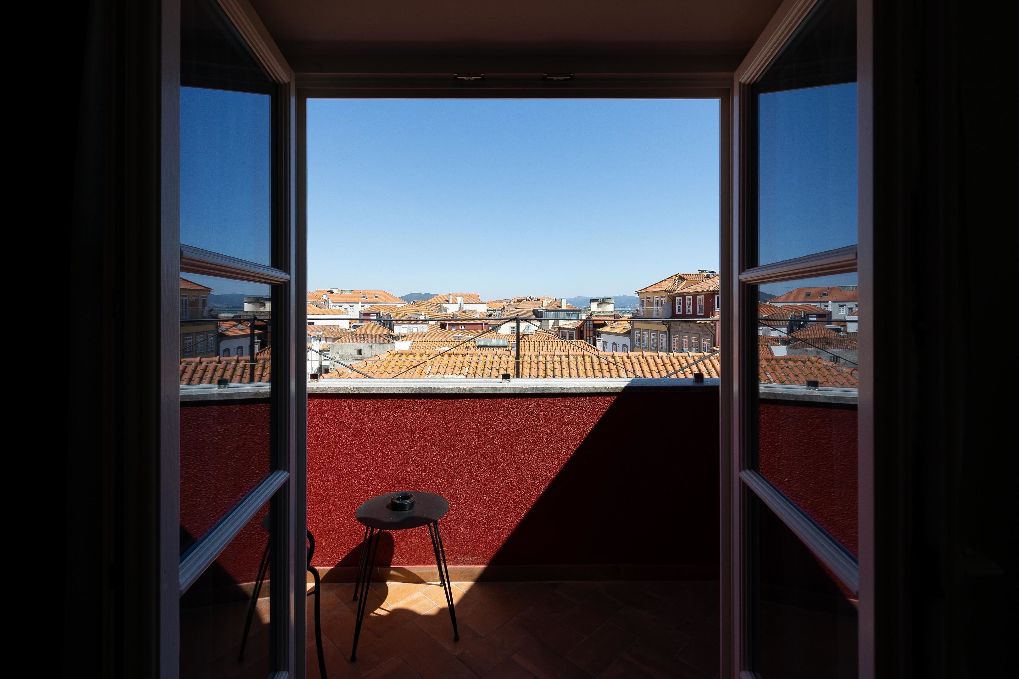 A balcony with a red wall, a small table, and a chair.